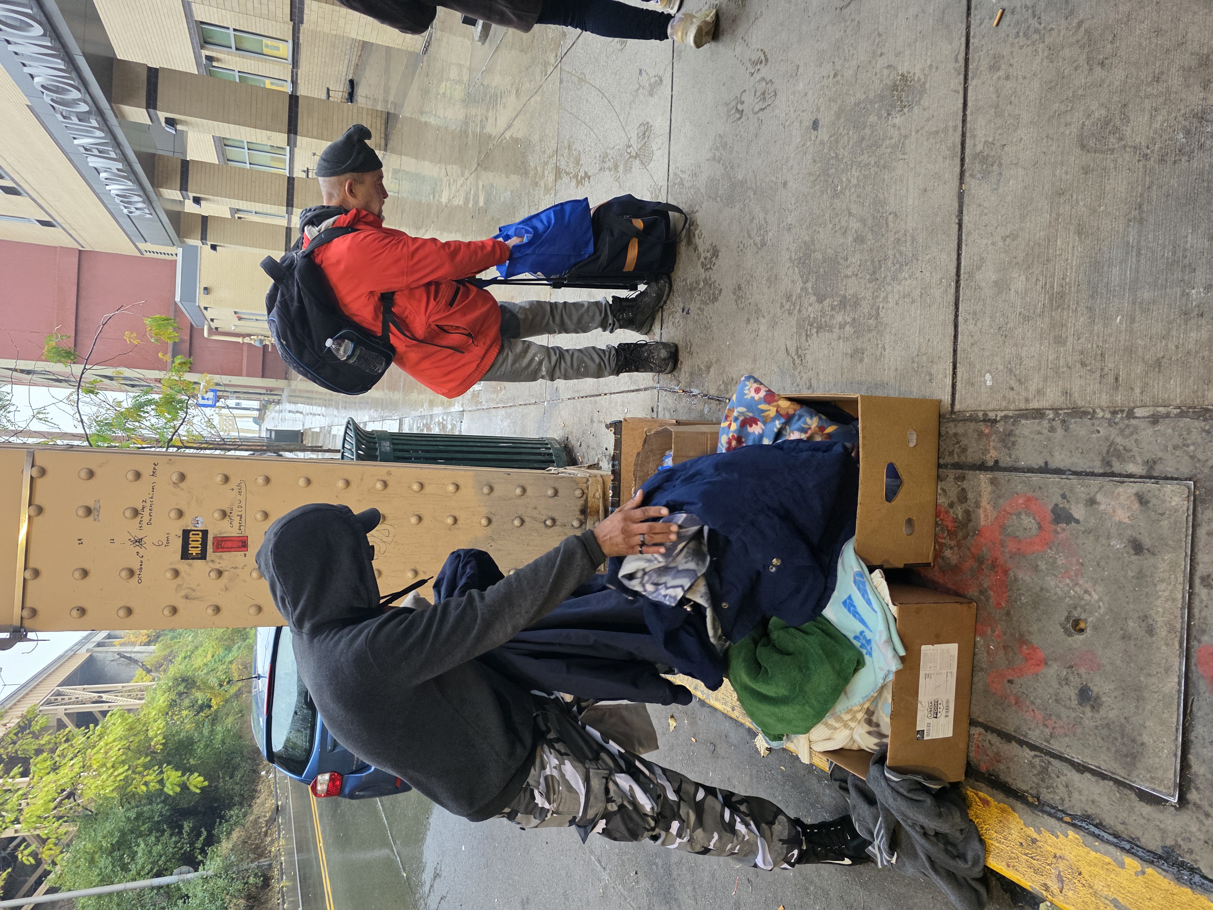 Community members selecting clothing from donation boxes on Second Avenue