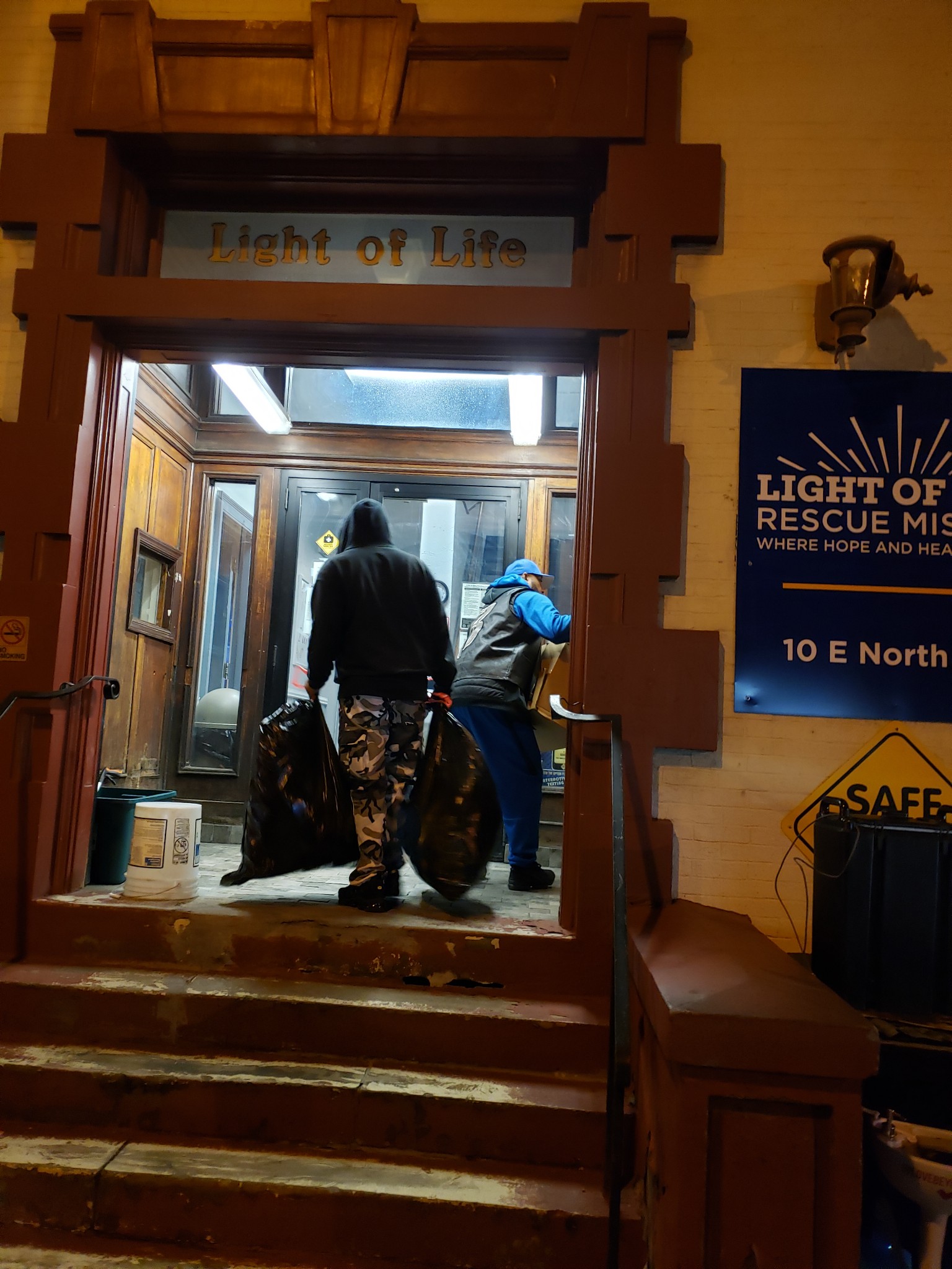 Volunteers carrying donations into Light of Life Rescue Mission at night