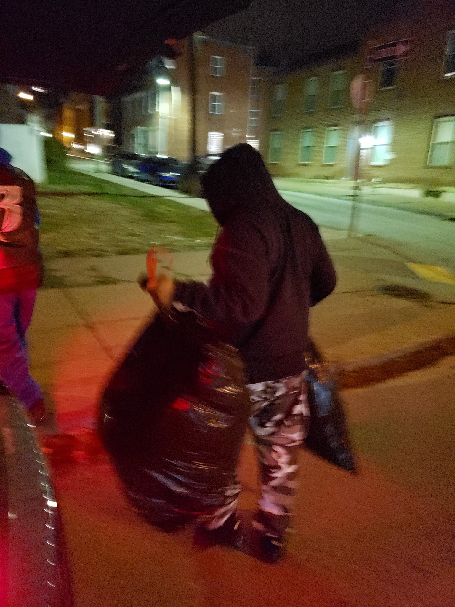 Volunteer carrying supplies through Pittsburgh neighborhood at night