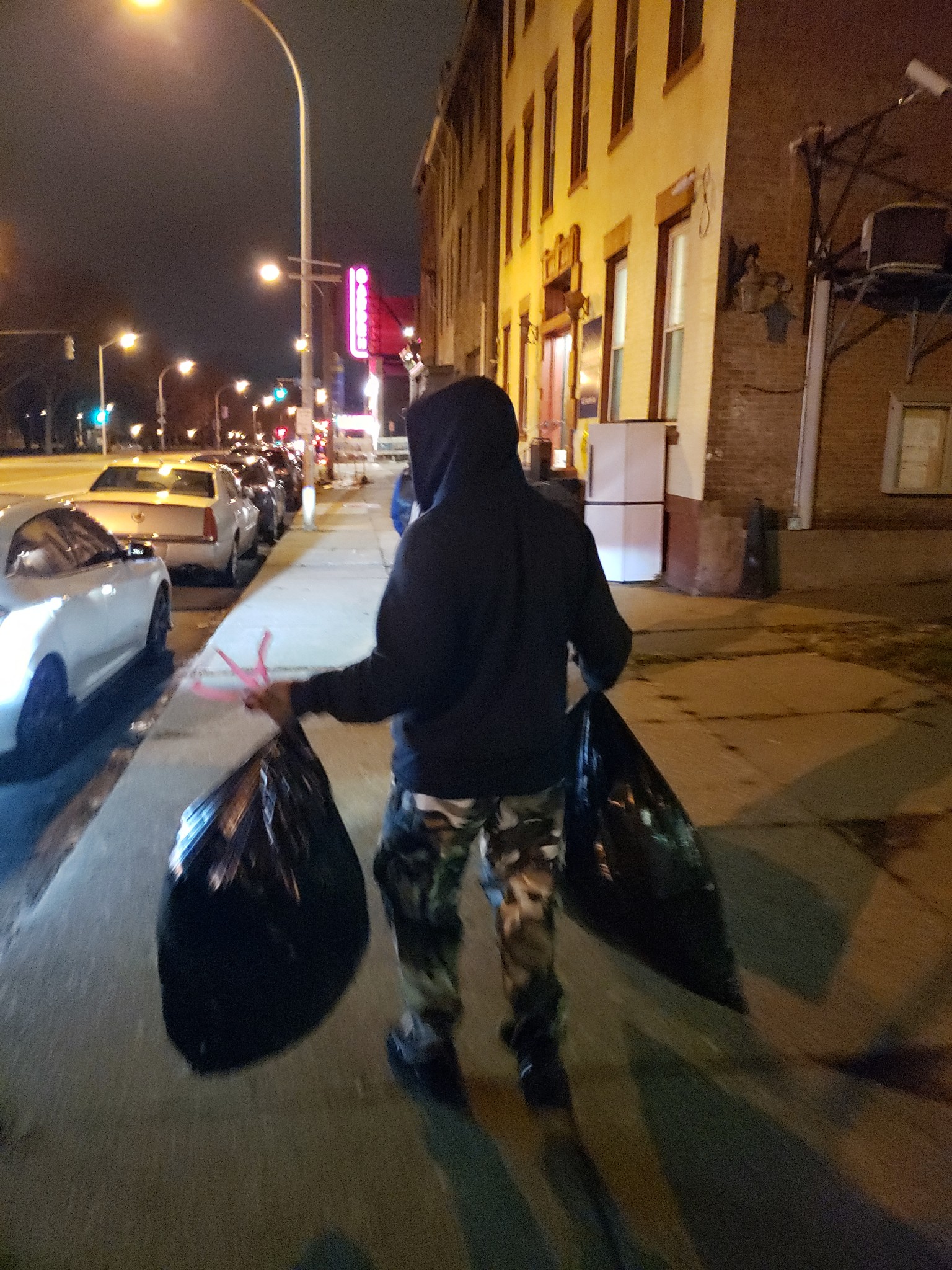 Volunteer walking with two large supply bags through Pittsburgh at night